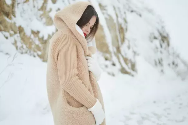 femme couverte par une veste à capuche beige dans la neige